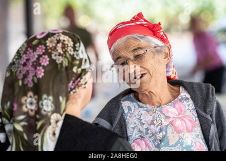 Eine Dame mit fehlenden Zähnen und ein rotes Kopftuch spricht mit ihrem Freund in einem Dorf in der Türkei Stockfoto