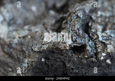 Versteinerte Lava in Makro Nahaufnahme, selektive konzentrieren. Anthrazitfarbene Vulkangestein im Detail mit Irisierendem Schimmer auf der Oberfläche, kopieren. Stockfoto