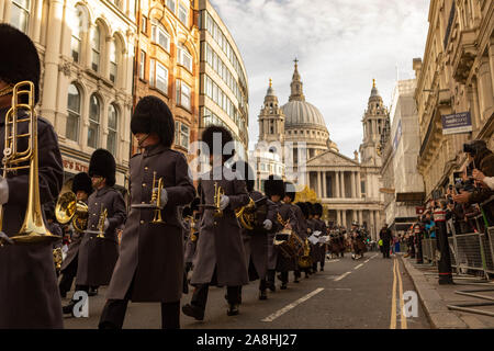 London, Großbritannien. November 2019. Uniformierte Musiker in zeremonieller Kleidung marschieren bei einer feierlichen Parade in London an der St. Paul’s Cathedral vorbei. In grauen Mänteln und Bärenfellhüten tritt die Blaskapelle vor Zuschauern auf, die die Straße säumen. Die Veranstaltung spiegelt die britische Militärtradition und das öffentliche Gedenken wider. Penelope Barritt/Alamy Live News Stockfoto