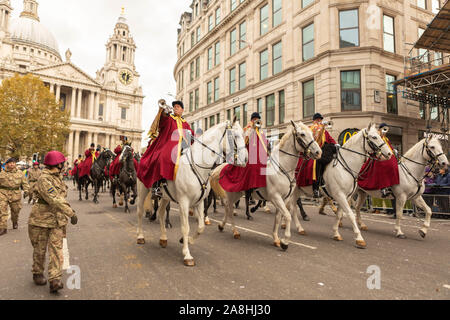 London, Großbritannien. November 2019. Eine zeremonielle Parade mit einer berittenen Militärkapelle in rot-goldenen Uniformen führt vor der St. Paul’s Cathedral in London vorbei. Reiter auf weißen und schwarzen Pferden tragen Messinginstrumente, begleitet von Soldaten in Tarnung und braunen Baskenmützen. Zuschauer säumen die Straße hinter Barrieren und beobachten den formellen Prozeß. Die Teilnehmer bewegen sich entlang des Ludgate Hill und nehmen an der Lord Mayors Show 2019 teil. Rund 7.000 Menschen, 200 Pferde, 150 Wagen und Marschkapellen werden erwartet. Penelope Barritt/Alamy Live News Stockfoto