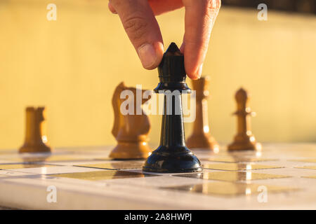 Finger verschieben einer Schachfigur auf einem Schachbrett in einem Park. Stockfoto