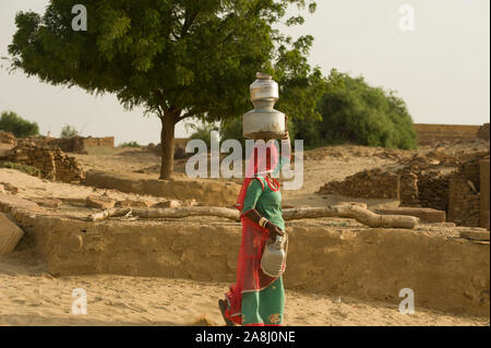 Jaisalmer, Rajasthan, Indien - 19. August 2011: Rajasthani, die Wasser Gläser in den Kopf in einem Dorf in der Wüste Thar Stockfoto