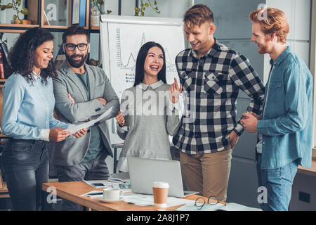 Startupers zusammen arbeiten im Büro stehen Reden lächeln lachen heiter Stockfoto