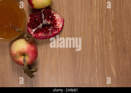 Stück reifer Granatapfel, Honig und Apfel auf einem hölzernen Hintergrund Stockfoto