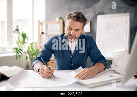 Schwere reifen Architekt Zeichnung neue Skizze auf Papier beim Sitzen durch Schreibtisch Stockfoto