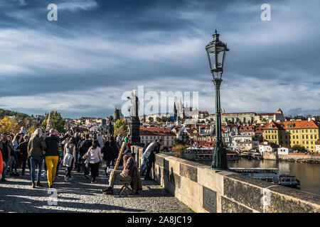 Prag, tschechische Republik - 27. Oktober 2019: Touristen und Händler an der Charles Brücke über den Fluss Moldau Vor Hradcany Castle und Saint Vitus Kath. Stockfoto