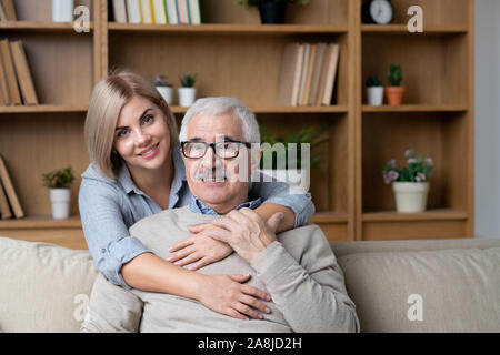 Gerne blonde junge Frau Froehlich senior Vater auf der Couch umarmt Stockfoto