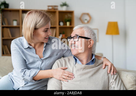 Erholsame älterer Mann und seiner jungen Tochter entspannt auf der Couch und sprechen zu Hause Stockfoto