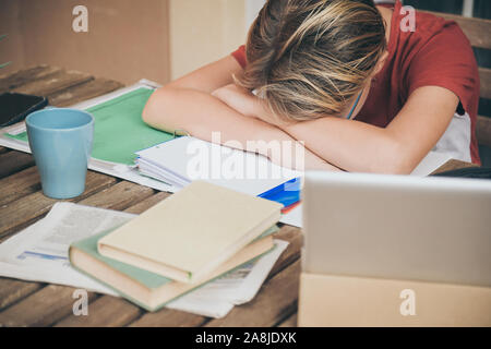 Müde Schüler Hausaufgaben zu Hause sitzen im Freien mit Schule Bücher und Zeitungen. Junge müde wegen der schweren studieren. Kind schlafend auf dem copybook nach l Stockfoto