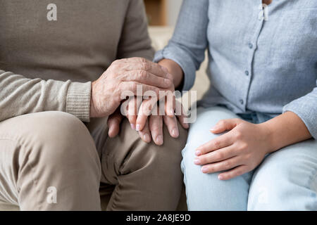 Älterer Mann in der casualwear seine Hand auf die von seiner jungen Tochter Stockfoto