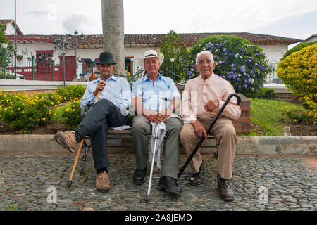 Drei Männer auf einer Bank in der Nähe von Concepción, Antioquia, Kolumbien sitzen. Stockfoto