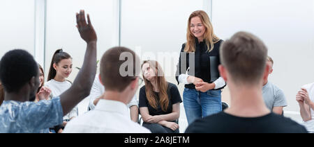 Junge Frau, die in einem Kreis ihrer Kolleginnen und Kollegen. Stockfoto