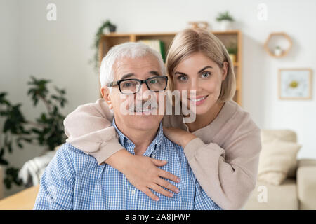 Junge lächelnde blonde Frau ihr Alter pensionierter Vater in Brillen umarmen Stockfoto