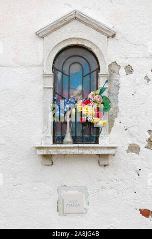 Schrein mit Blumen und eine Statue der Jungfrau Maria in der Wand eines Gebäudes in Venedig, Italien Stockfoto