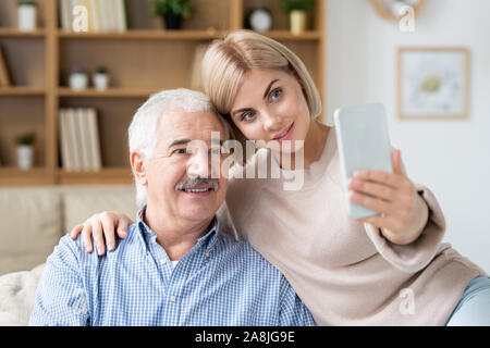 Junge zärtlich blonde Frau mit ihrem alten Vater, während Sie selfie Stockfoto