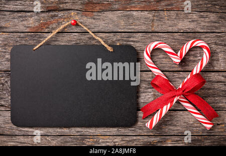 Weihnachten Zuckerstangen in der Form eines Herzens mit leeren Kreidetafel Zeichen Stockfoto