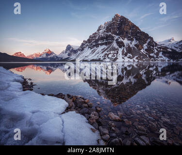 Ruhe Frühjahr Abend in Bow Lake mit Crowfoot Mountain spiegelt sich auf dem Spiegel wie Wasser. Schnee Landschaft Nationalpark Banff, Canadian Rockies Stockfoto