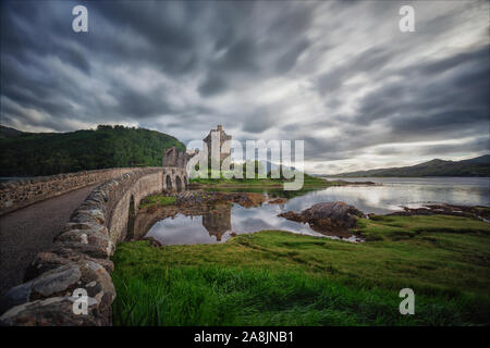 Eilean Donan Castle, eine schottische Schloss auf der Insel durch eine Brücke in ein Loch verbunden. Schottland Highlands. Bewölkten Tag, Reflexion über Spiegel Gewässern Stockfoto