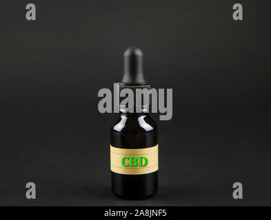 Multipurpose cannabidiol CBD öl Konzept. Infusion in Braun dropper Flasche auf dunklen schwarzen Hintergrund. Stockfoto