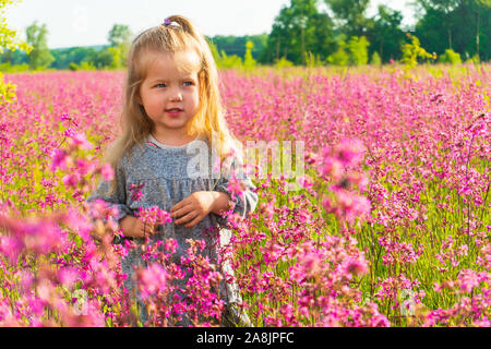 Kleine Mädchen stehen im Bereich der rosa Blüten Stockfoto