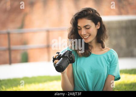 Fotograf Mädchen sitzen auf dem Gras an der Kamera Bildschirm schaut lächelnd Stockfoto