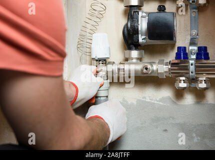 Ein Arbeitnehmer ist die Installation einer thermischen Kopf auf der Startseite Heizung system Distributor. Stockfoto