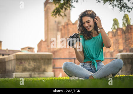 Fotograf Mädchen sitzen auf dem Gras an der Kamera Bildschirm schaut lächelnd Stockfoto