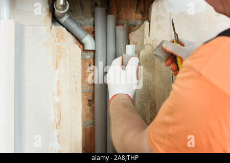 Die Hand des Arbeiters ist Holding Isolierung Heizungsrohre für zu Hause. Stockfoto