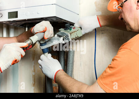 Der Arbeiter ist Löten Kunststoff Rohre und eine Verbindung zu einem inländischen Gas Boiler. Stockfoto