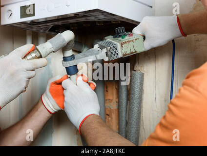 Der Arbeitnehmer ist Löten Kunststoff Rohre und eine Verbindung zu einem inländischen Gas Boiler. Stockfoto