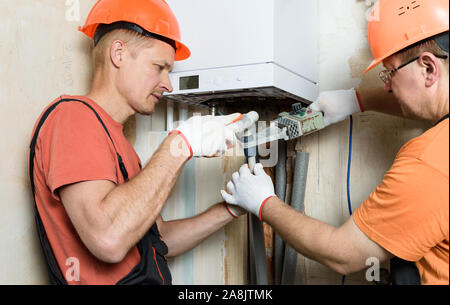 Die Arbeiter sind Löten Kunststoff Rohre und eine Verbindung zu einem inländischen Gas Boiler. Stockfoto