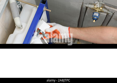 Ein Arbeitnehmer ist das Einfügen der Toilettenspülung Ventil in den eingebauten Tank. Ansicht von oben. Stockfoto