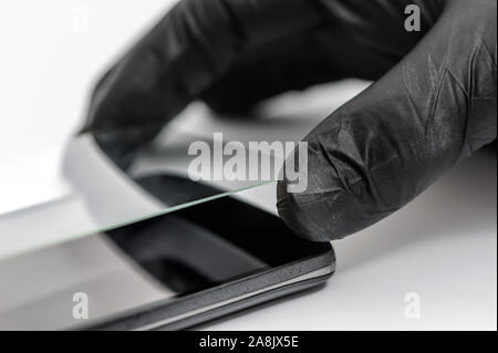 Ein Mann ist ein Schutzglas auf dem Bildschirm eines Smartphones. Stockfoto