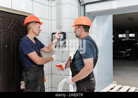 Elektriker installieren Die wall Verdrahtung. Ziehen Sie die Drähte in die Rohre. Stockfoto