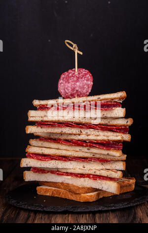 Heep von Sandwiches geröstetes Brot und Salami auf Schwarz. Fast food ungesunde Konzept Stockfoto