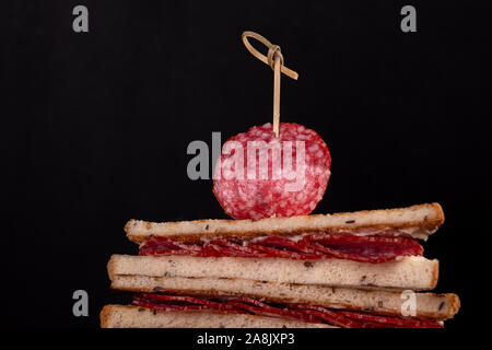 Heep von Sandwiches geröstetes Brot und Salami auf Schwarz. Fast food ungesunde Konzept Stockfoto