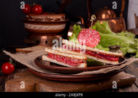 Heep von Sandwiches geröstetes Brot und Salami auf Holztisch. Fast food ungesunde Konzept Stockfoto