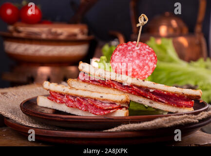 Heep von Sandwiches geröstetes Brot und Salami auf Holztisch. Fast food ungesunde Konzept Stockfoto