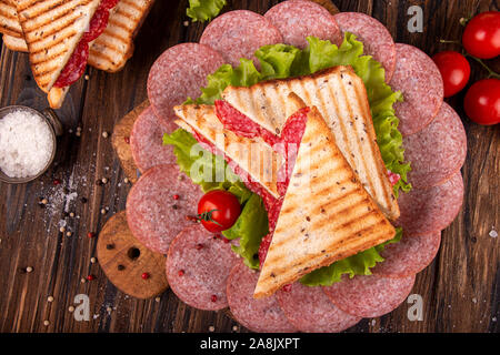 Heep von Sandwiches geröstetes Brot und Salami auf Holztisch. Fast food ungesunde Konzept. top View Stockfoto