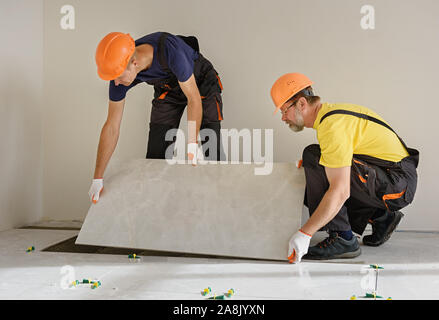 Arbeitnehmer zur Montage einer großen Keramische Fliese auf dem Boden. Stockfoto