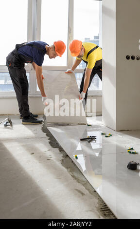 Arbeitnehmer zur Montage einer großen Keramische Fliese auf dem Boden. Stockfoto