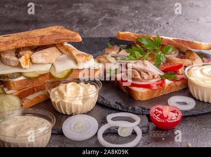 Sandwiches mit Hähnchen Fleisch, Cherry Tomaten, Zwiebeln und Hühnerfleisch, marinierten Gurken, Mozzarella auf schwarzem Hintergrund Stockfoto