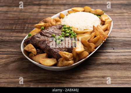 Rindersteak mit rustikalen Kartoffel- und ricei auf Holztisch, Hintergrund, weiches Licht Stockfoto