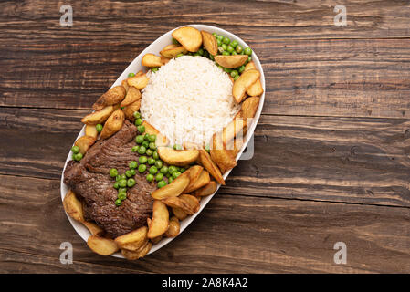 Rindersteak mit rustikalen Kartoffel- und ricei auf Holztisch, Hintergrund, weiches Licht Stockfoto