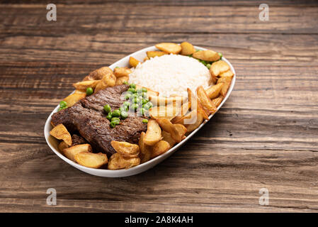 Rindersteak mit rustikalen Kartoffel- und ricei auf Holztisch, Hintergrund, weiches Licht Stockfoto