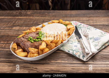 Rindersteak mit rustikalen Kartoffel- und ricei auf Holztisch, Hintergrund, weiches Licht Stockfoto