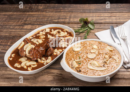 Risotto mit Filet Mignon. Risoto und Rindfleisch mit Pilzen in einer weißen Platte auf einem weißen Hintergrund. Weiches Licht. Italienisches Essen. Stockfoto