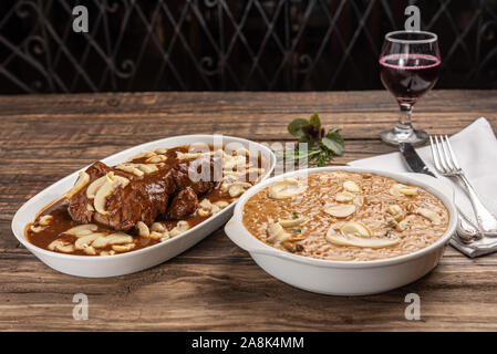 Risotto mit Filet Mignon. Risoto und Rindfleisch mit Pilzen in einer weißen Platte auf einem weißen Hintergrund. Weiches Licht. Italienisches Essen. Stockfoto