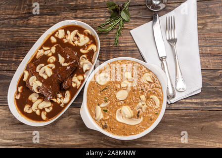 Risotto mit Filet Mignon. Risoto und Rindfleisch mit Pilzen in einer weißen Platte auf einem weißen Hintergrund. Weiches Licht. Italienisches Essen. Stockfoto