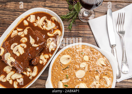 Risotto mit Filet Mignon. Risoto und Rindfleisch mit Pilzen in einer weißen Platte auf einem weißen Hintergrund. Weiches Licht. Italienisches Essen. Stockfoto